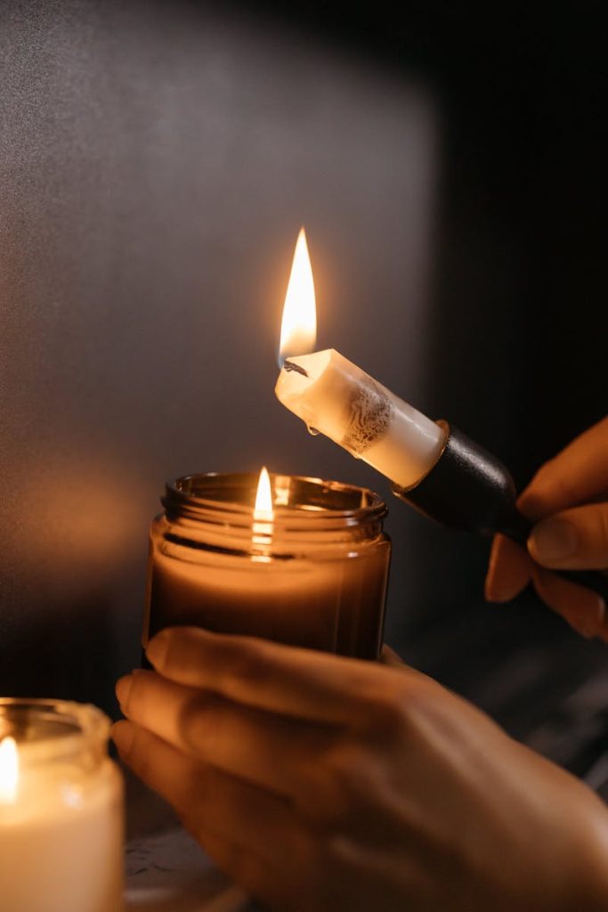 Close-up of hands lighting a candle, creating a warm and cozy ambiance indoors.